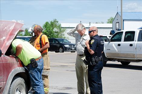 Vehicle owner Giles Gordon stands with Ronan Police Officer  Corey White to inspect the damage.