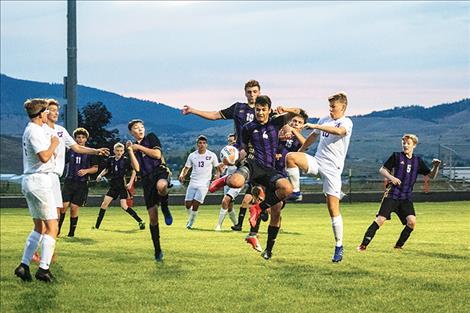 Polson Pirate soccer players jump in the air after the ball.