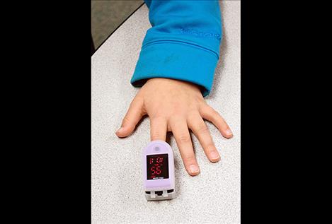 An elementary student has their heart rate and oxygen levels read.