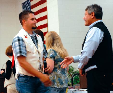 Brandon Gerrity, who earned a  Bachelor of Science degree in Forestry Wildland Fire, prepares to shake the hand of Confederated Salish and Kootenai Tribes Tribal Council Chairman Joe Durglo.