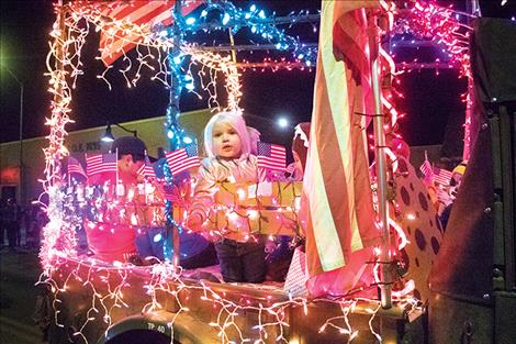 Children wave flags as parade participants represent branches of the military.