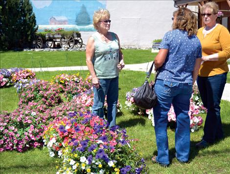 Ky Bartel and Ronna Walchuk of the Ronan Beautification Committee visit with Kathy Sykes as they prepare to hang 36 baskets in 