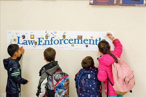 children sign their names to a banner that was later given to police officers to express appreciation for all the work they do.