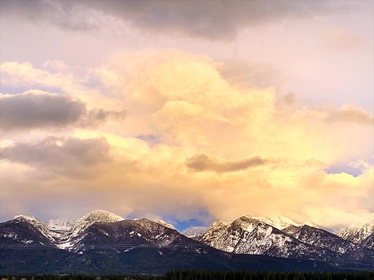 Evening light: Alpine glow and the clouds above illuminate snow-capped mountains east of Ronan on Feb. 23.