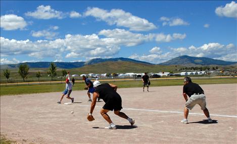 Lake County Sheriff Jay Doyle reaches third base. Finley Point Fire Department’s Monty Marengo, center, backs up the third baseman as umpire Shawn Wilson keeps an eye on the proceedings.