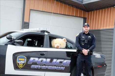 Ronan Police Officer Chris Moldenhauer watches over the bear in his patrol car.