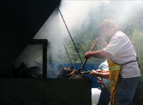 Longtime firefighter Ray Frey braves the smokey heat of the grill as he prepares barbecued food for more than 700 people at Saturday’s Fireman’s Picnic in St. Ignatius.