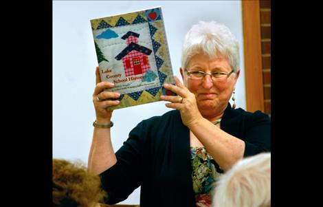 With a smile on her face, Joyce Decker Wegner holds up a copy of Volume II of the Lake County School History.