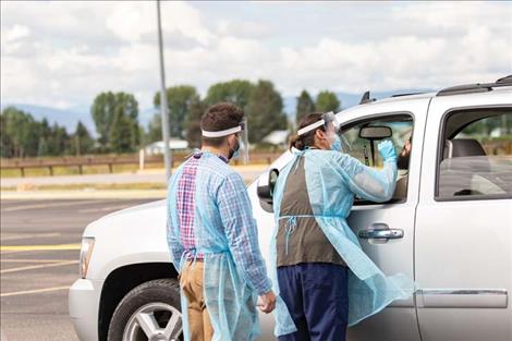 Rob Zolman / Valley Journal  A healthcare worker reaches into a car to do a nasal swab test during the drive-through COVID-19 testing event on Thursday in Pablo.  