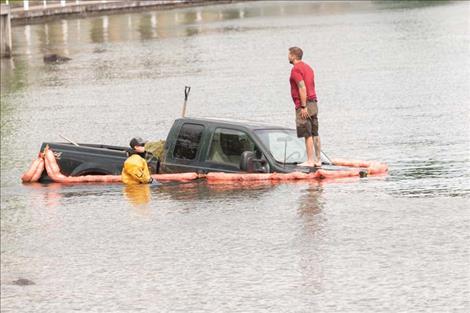 Members of the LCSAR rescue crew stand on the truck and in the water to prepare the  vehicle for removal from the lake on Saturday after the crash.  