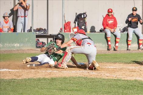 Mariner Ethan McCauley slips under the catcher’s tag for a score.