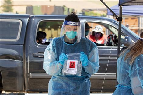 A healthcare worker closes a sample bag for shipment to the lab.