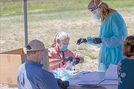 Health care workers prepare a COVID-19 sample for the testing lab.