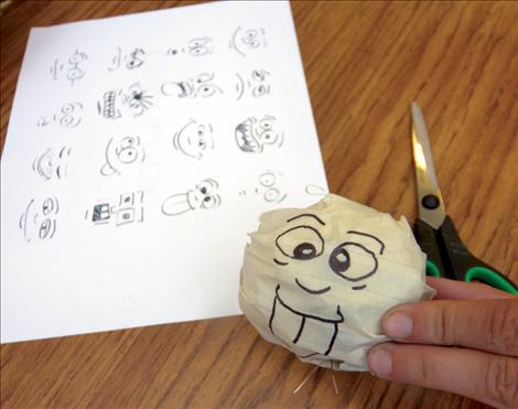 Art camp participants draw faces for their marionettes.