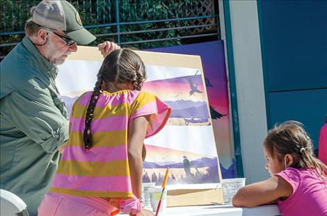 Photos by Karen Peterson / Valley Journal  Children from the Boys and Girls Club study what the finished mural will look like to decide what they would like to draw on their own paper. Below: the artist adds the hand print to  honor missing or murdered indigenous women. 