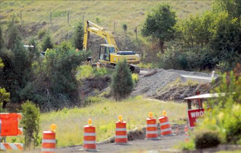 An excavator chews into the earth on Skyline Drive as contractors prepare to install walls. 