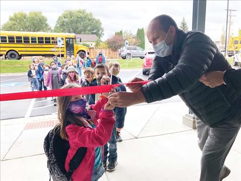 Aric Cooksley helps a youngster with the ribbon cutting at the new Polson club Monday.