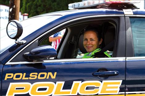 Polson police officer Devon McCrea smiles from her police car as she cruised in Polson's 4th of July parade.