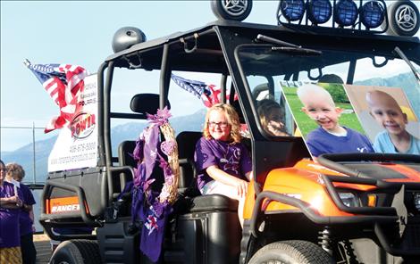 Grand Marshals Brynn Pule, 9, Cole Whitworth, 6, and Jade Marr, 2 ride around the track during the survivors’ lap.