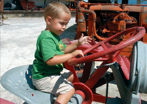Leroy Burland, 2, grabs the steering on a Ford tractor.