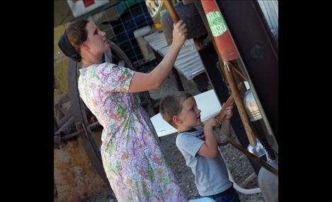 Rene and Branson Koehn try hammers and wooden sticks to ring the metal objects, such as kettles and gas cans.