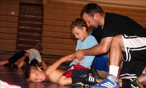 Cody Dillard, 9, uses Ian Sharrard, 7, left, to practice his wrestling technique with the help of Coach Cronk.