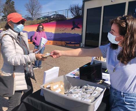 Lisa Dionne collects her free packet of wildflower seeds from Big Sky Watershed Corps member Abby Schmeichel during Pollinator Week, sponsored by the Lake County  Conservation District.