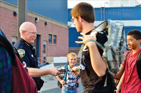 Ronan Police Chief Ken Weaver hands out pencils to children at the Ronan School District as one of his projects to build community connections several years ago