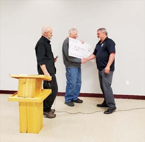 Polson Shooters Association President Rob St. Clair, left, and Treasurer Mauri Morin, center, present Polson Police Chief Wade Nash, right, with a $900 donation at their annual banquet April 22 at the Polson VFW.