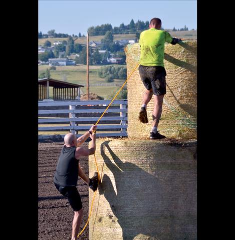 First-place finisher Rob LaBair of Polson, top, traverses a two-story round bale on his way to the finish line, followed closely by Mark Murphree of Ronan.