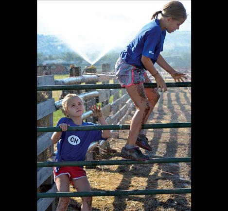 Collen and Montana Korella scale a fence along the obstacle course.