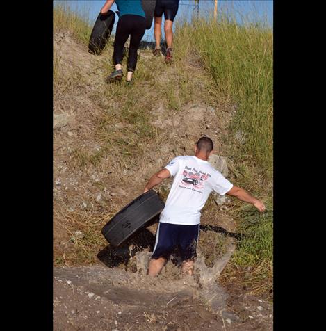 Participants carry tires up a steep hill along the obstacle-course style run.