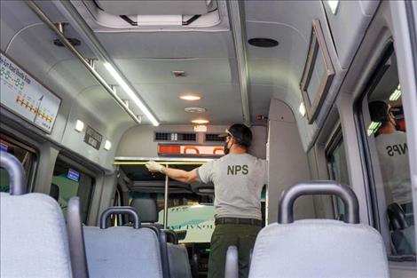 Park employee Mark Boles takes measurements for installing a vinyl barrier as part of COVID-19 mitigations for a Glacier National Park shuttle.