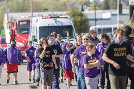 Holding the Flame of Hope up as high as she can, Special Olympian Rose Edge makes her way down Main Street during the Law Enforcement Torch Run on Thursday in Polson.