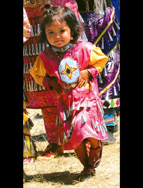 With her hands on her hips, a tiny jingle dancer dances in the Grand Entry.