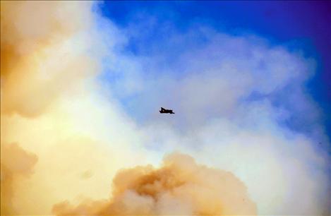 A fire tanker is dwarfed by billowing smoke Saturday after spraying fire retardant on the Firestone Flats fire near Arlee.