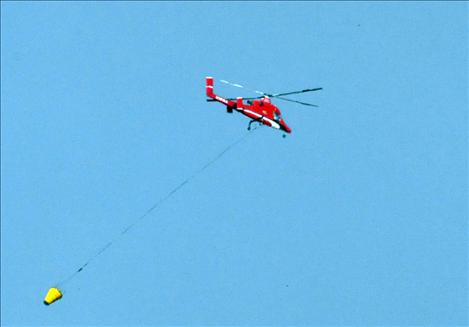 A fire-fighting helicopter flies overhead.