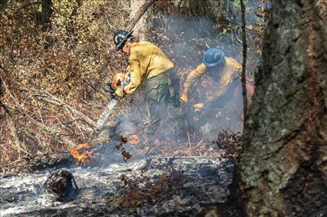 Wildfire crew members perform mop up work along the Boulder 2700 fire containment line over the weekend.