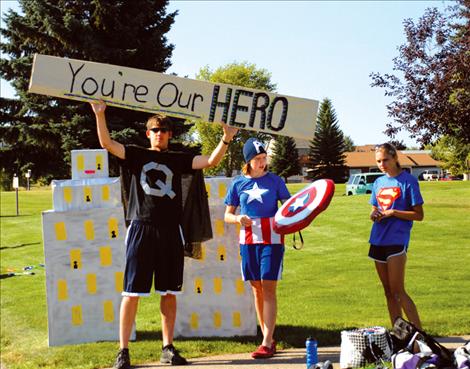 Quinn Harlan, left, Tegan Bauer and Amanda Stobie help man the Polson High School Cross Country Team aid station during the Polson Triathlon. Their theme was superheroes, and they had special cheers for their cross country coach Matt Seeley.