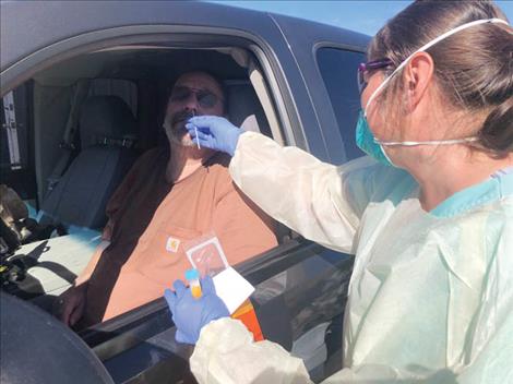 Liliya McGuinness, a registered nurse at Providence St. Joseph Medical Center, administers a COVID test to Mike Johnson at the drive-through testing site in Polson.