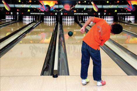 A young bowler leans in the direction he hopes his ball to go during a visit to the bowling alley last week with other K-3 students from the migrant school program in Polson. Students visited the bowling alley as part of a celebratory final week of school.