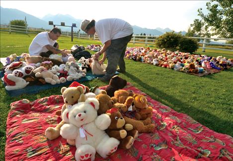 Cowen’s friend Chris Irvine, right, and his son Cameron spent hours setting up for Saturday’s garage sale, artistically placing thousands of bears around the yard.