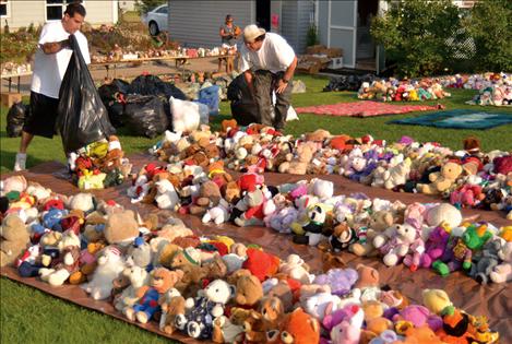 Cowen’s friend Chris Irvine, right, and his son Cameron spent hours setting up for Saturday’s garage sale, artistically placing more thousands of bears around the yard.
