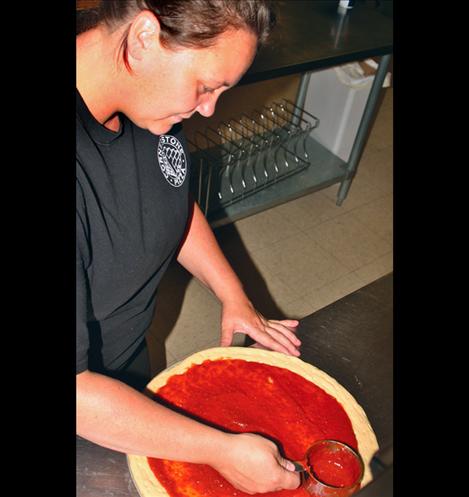 Rose Mansell, team leader, works over a sauce swirl on a pizza.