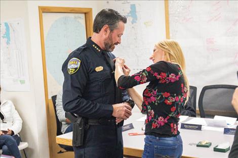 Kristin Jacobson pins the chief badge on her husband, new Ronan Police Chief Robert Jacobson, after he was sworn in during the Nov. 8 city council meeting.