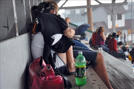 People in the stands huddle up as hail bounces off the tin roof of the rodeo arena.