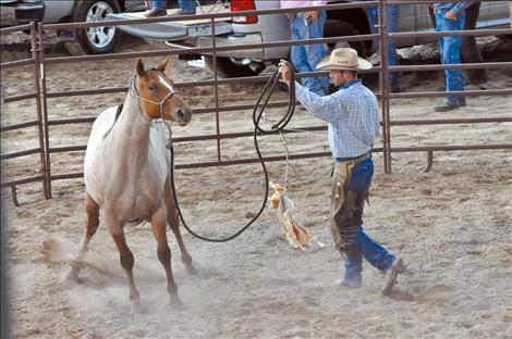 Joshua Senecal starts toward a horse with a hanging object to train it. 