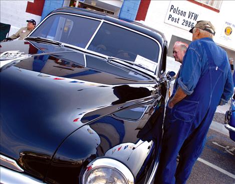 Aged yet shiny, a classic car draws the eyes of two men who strolled through the car show.
