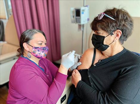 Annette Olsson receives her COVID-19 booster from St. Luke Nurse Wendy Last Star.