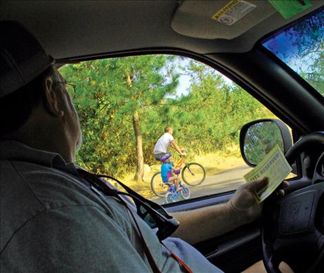 Camp host Dave Gray, above, watches a couple of campers as they bike along the road in Big Arm State Park. Gray says he wants everyone to enjoy themselves and have a good time.